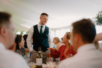 Man standing and talking at a wedding reception.