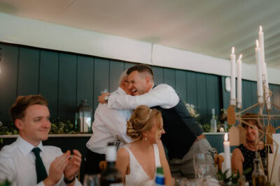People hugging and smiling at a wedding reception.