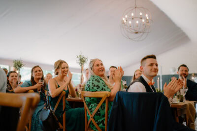 People clapping and smiling at a gathering.