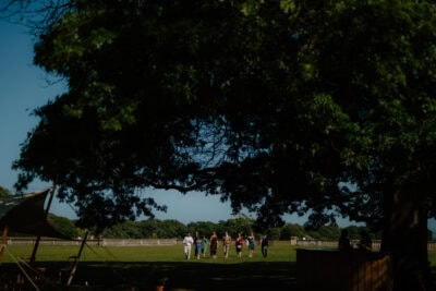 People walking in a sunny park under trees.