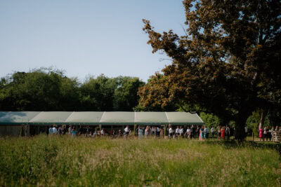 Outdoor event with marquee and people in meadow.