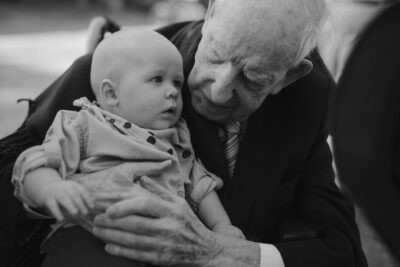 Older man holding baby in thoughtful moment.