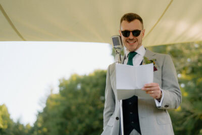 Man in suit reading speech at outdoor event.