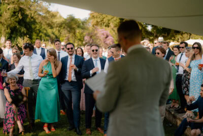 Guests laughing during outdoor wedding speech.