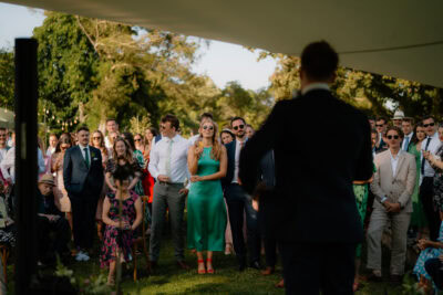 Guests at outdoor wedding reception listening to speech.
