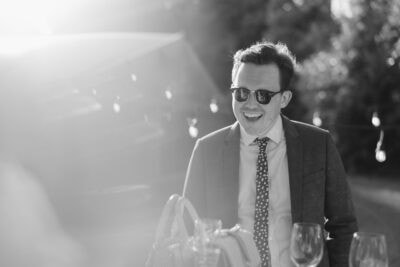 Man in sunglasses, smiling at outdoor event.