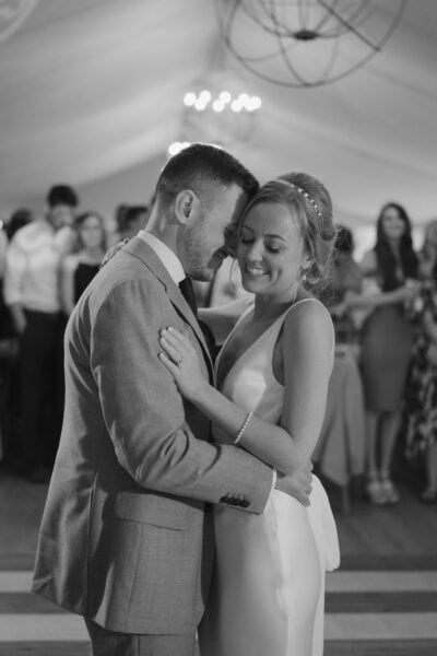 Couple dancing at wedding reception, smiling joyfully.