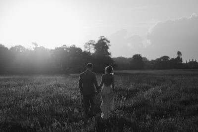Couple walking in a field at sunset.