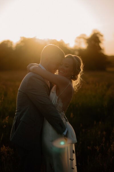 Couple embracing at sunset in a field.
