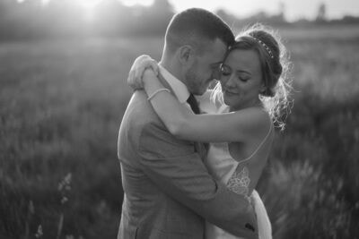 Couple embracing in a sunlit field.