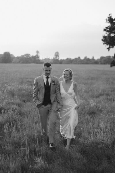 Couple walking in field during wedding.