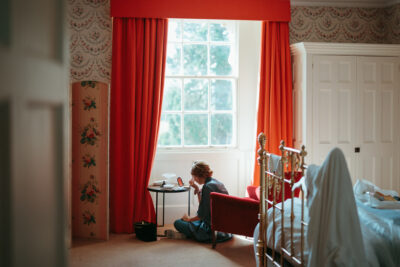 Woman reading by window in cozy bedroom.