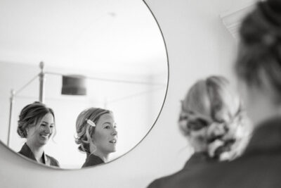 Woman smiling, reflection in round mirror, black and white photo