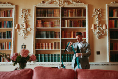 Man in suit adjusting tie in vintage library.