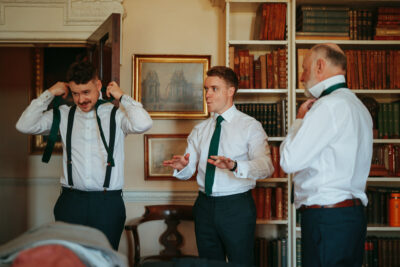 Men adjusting attire in a library with vintage books