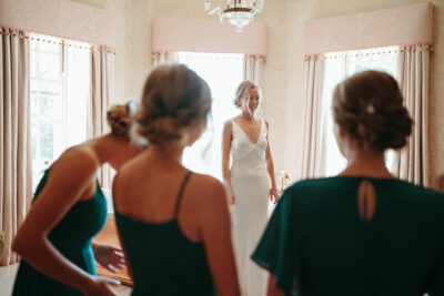 Bride smiling at bridesmaids in elegant room.