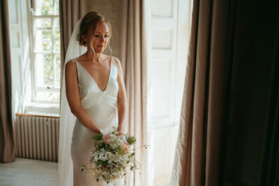 Bride holding bouquet in elegant wedding dress.