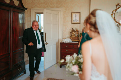 Wedding day, father sees bride, joyful room.