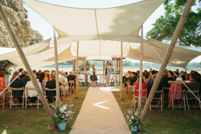 Outdoor wedding ceremony under tent with guests.