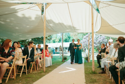 Outdoor wedding ceremony with guests and walking couple.