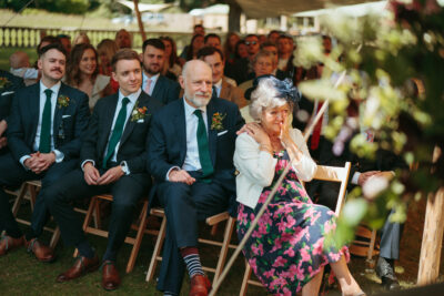 Wedding guests attentively watching ceremony outdoors.