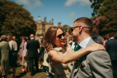 Couple embracing at sunny outdoor wedding event.