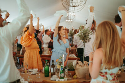 Guests dancing at wedding reception under tent.