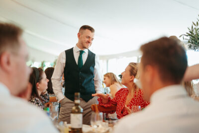 Man smiling at wedding reception table.