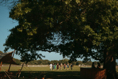 Group walking in sunlit park with large tree.
