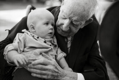 Elderly man holding and looking at baby