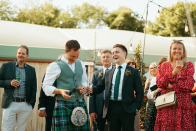 Wedding guests laughing during outdoor celebration.