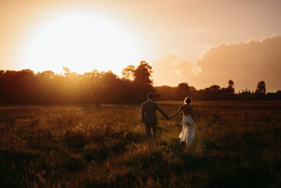 Couple holding hands in sunset-lit field