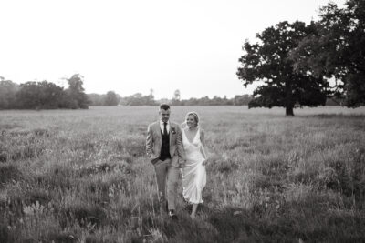 Couple walking in meadow on wedding day.