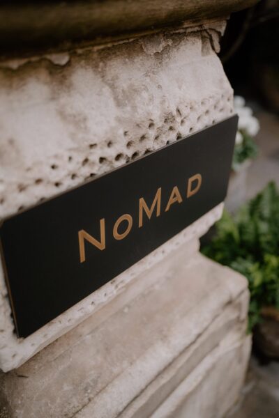 NoMad hotel sign on textured stone wall.