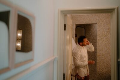 Man adjusts hair in hotel bathroom mirror.