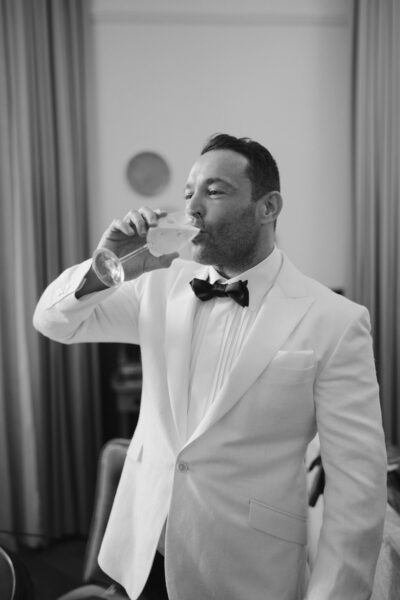 Man in tuxedo drinking champagne indoors