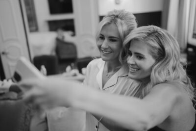 Two women taking a selfie indoors, smiling.
