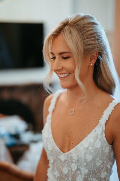 Bride smiling in elegant white wedding dress.