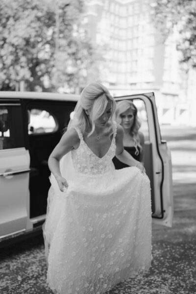 Bride stepping out of car in wedding dress.