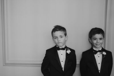 Two boys in suits, smiling and standing together.