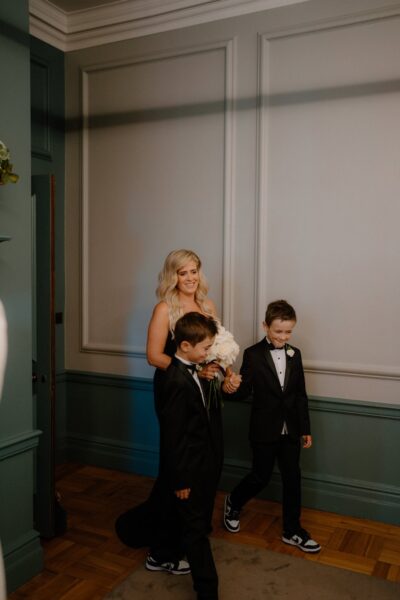 Smiling woman with flowers and two young boys.