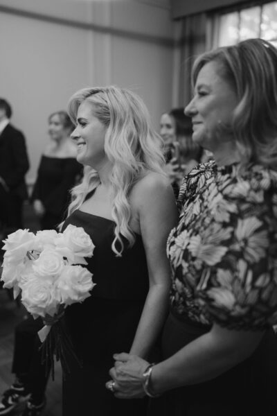 Smiling women with bouquet at formal event.