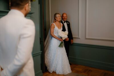 Bride enters with flowers, groom in foreground.