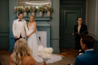 Couple holding hands during indoor wedding ceremony.