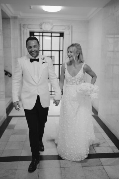 Bride and groom walking, holding hands, smiling.