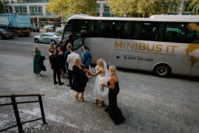Wedding guests boarding minibus in London street
