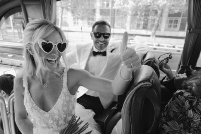 Bride and groom smiling on a bus.