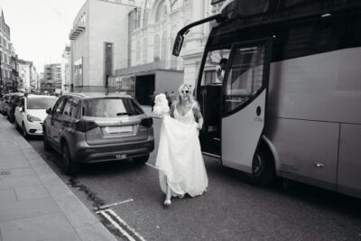 Bride in sunglasses exiting a coach on street