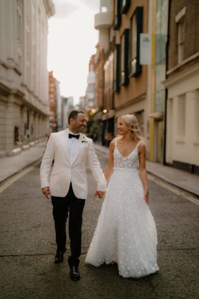 Bride and groom walking on city street