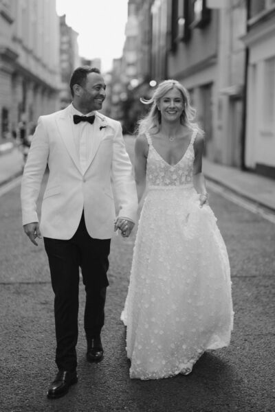 Couple walking joyfully in wedding attire.